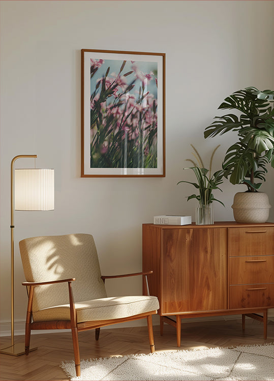 ein gemütliches Wohnzimmer mit einem Holzschrank, einem beigen Sessel, einem gerahmten Bild mit rosa Blumen und einer Topfpflanze.