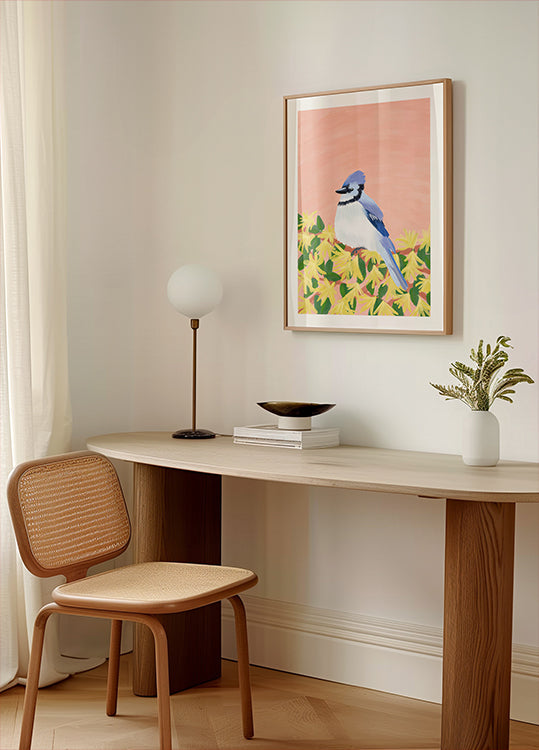 Eine gemütliche Zimmerecke mit einem Holzschreibtisch, einem geflochtenen Stuhl, einer Lampe und einem gerahmten Bild eines blauen Vogels auf gelbem Hintergrund.